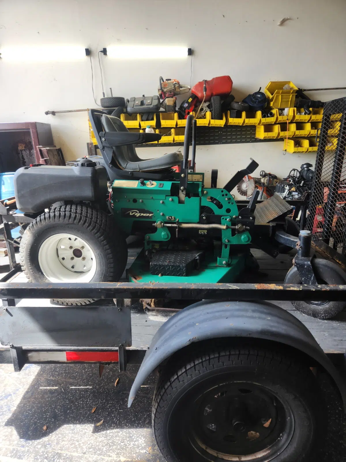 Green zero-turn riding mower strapped on a trailer — Tri County Small Engine Repair in Cape Coral