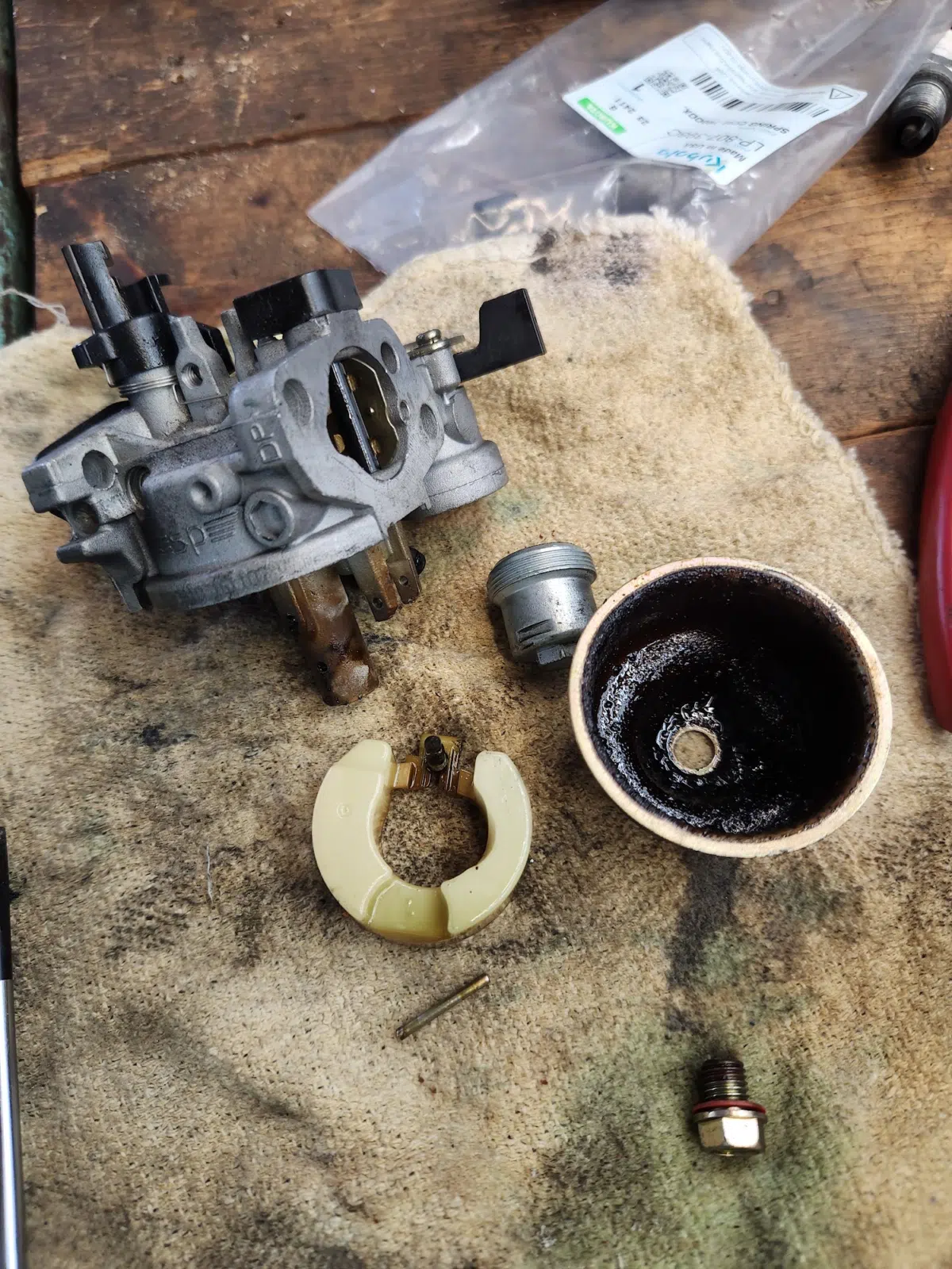Disassembled carburetor and fuel bowl parts on a shop rag — Tri County Small Engine Repair in Cape Coral